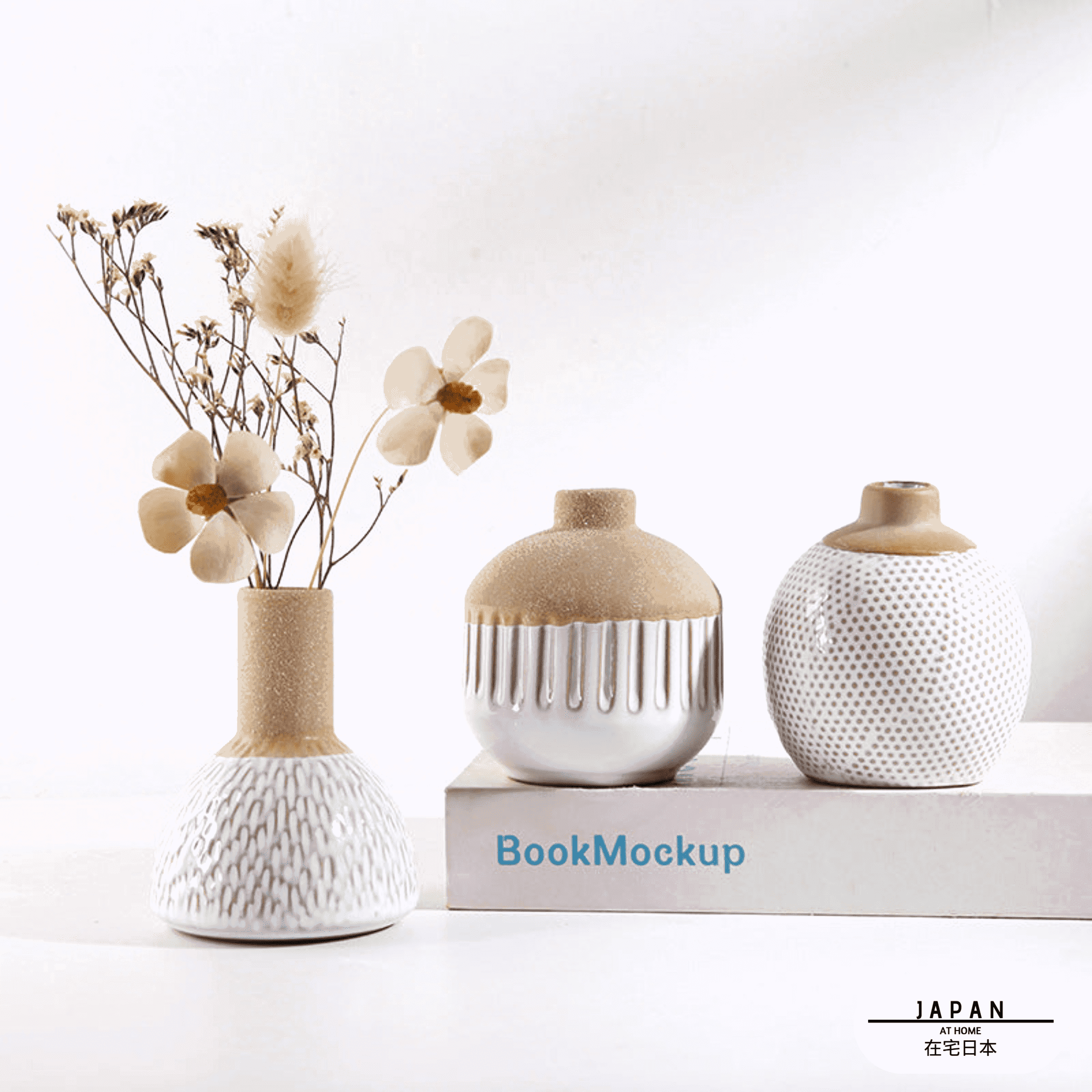Trois vases japonais Shizuka avec des fleurs séchées, deux posés sur un livre