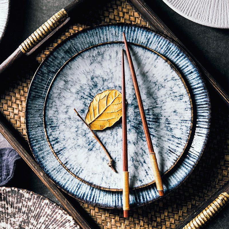 Assiettes Shiro marbre gris empilées avec baguettes et feuille séchée