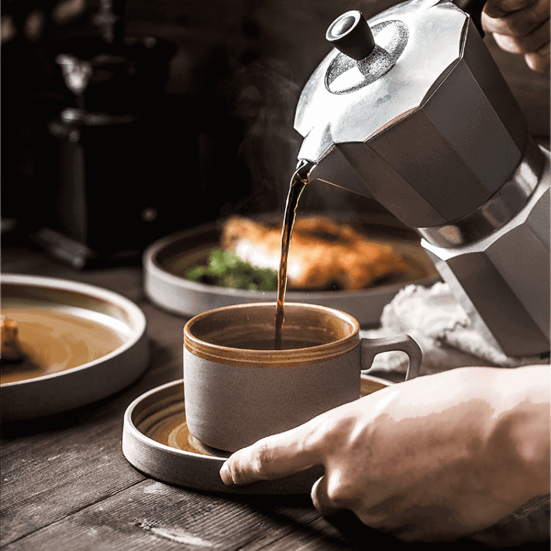 Café versé dans la tasse Konyo, assiettes garnies en arrière-plan