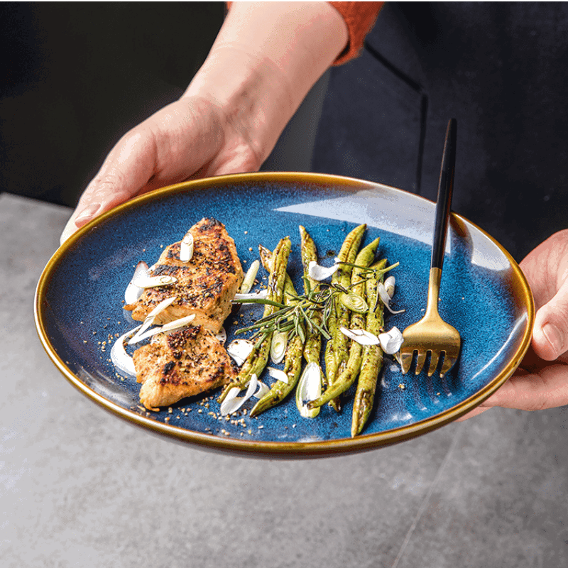 Assiette japonaise Tatsuzo bleue garnie de poulet et haricots verts, tenue à deux mains