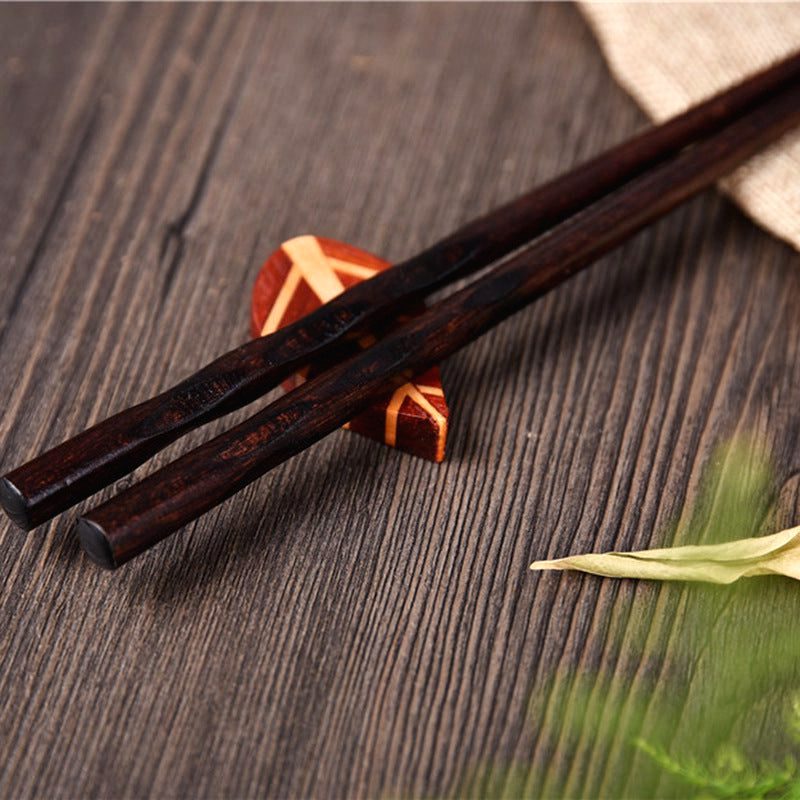Paire de baguettes en bois sombre sur un repose-baguettes, gros plan