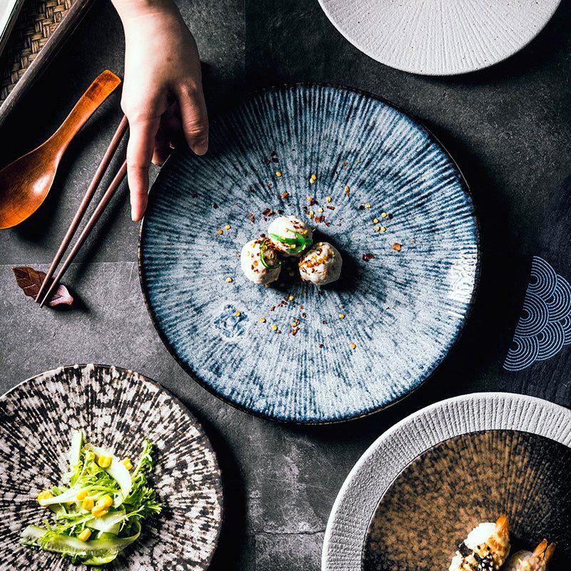 Main posant une assiette Shiro marbre gris garnie de bouchées