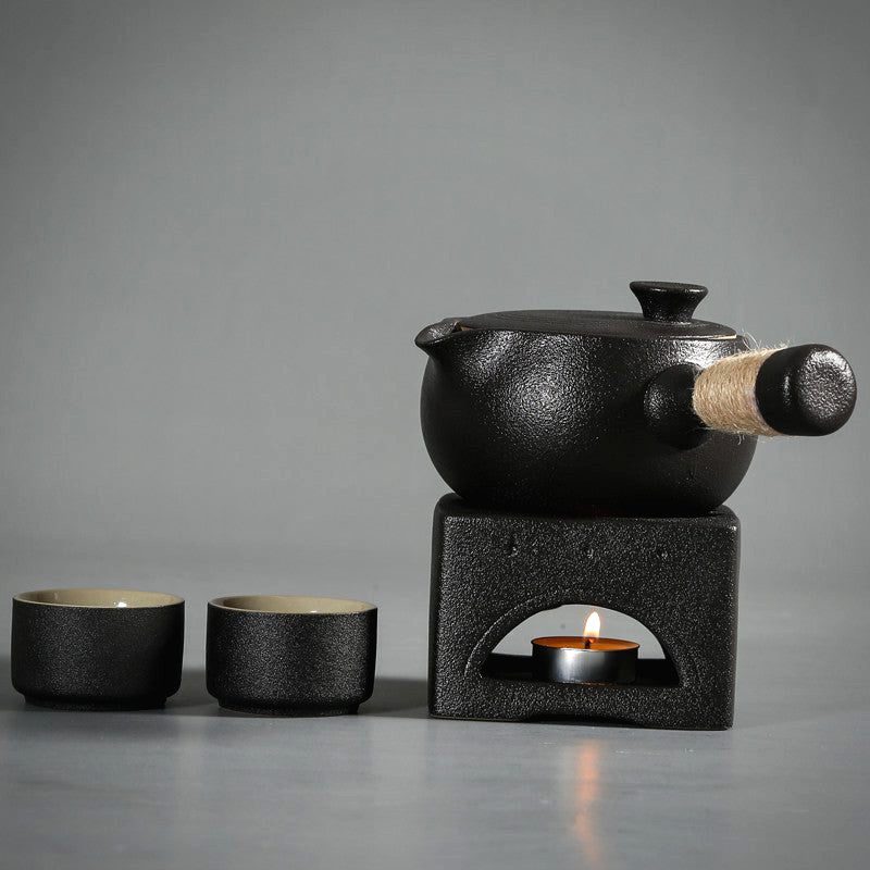 Théière noire sur son réchaud avec deux tasses assorties