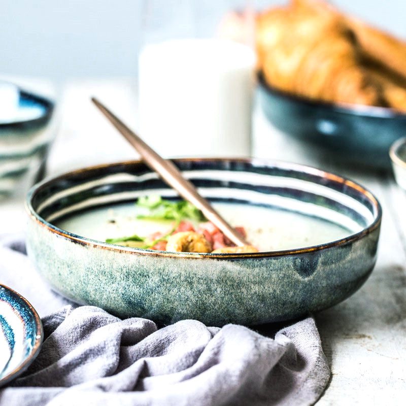 Assiette creuse Shintani garnie de salade avec cuillère en bois, sur un linge gris