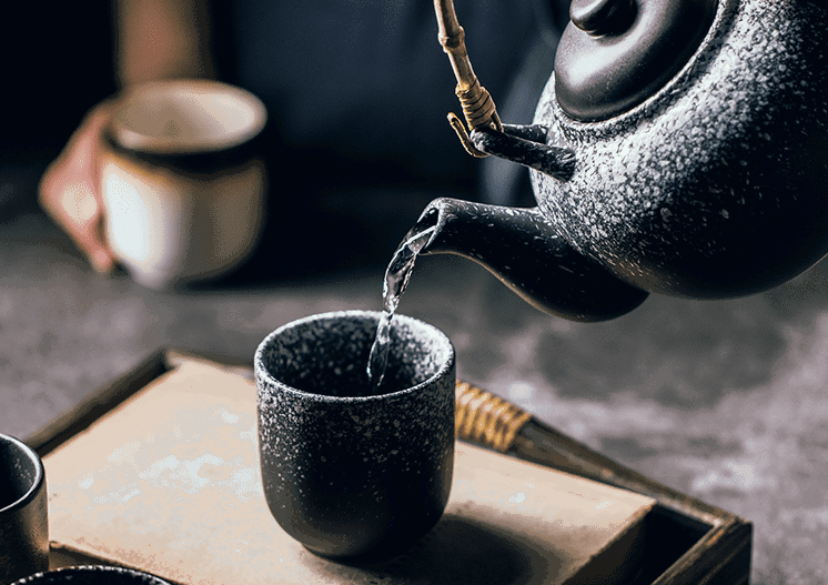 Thé versé d'une théière dans une tasse Ishikura noire