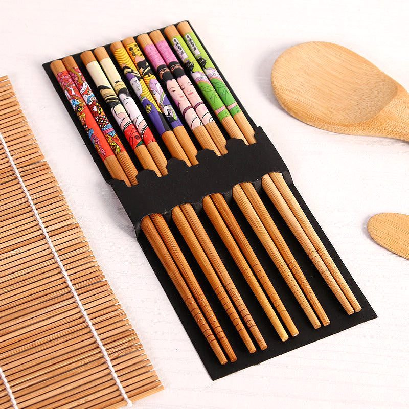 Baguettes décorées du kit sushi dans leur étui, natte en bambou à côté