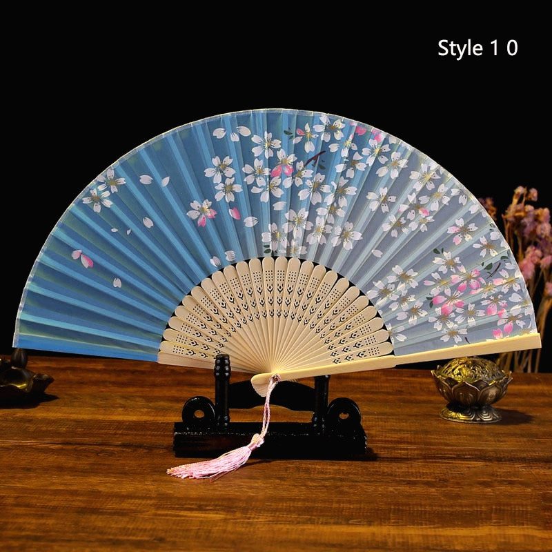 Éventail japonais en satin bleu ciel, fleurs roses, posé sur un support