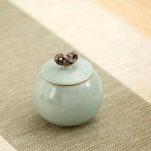 Boîte à thé Urishido verte à couvercle et bouton, posée sur une nappe