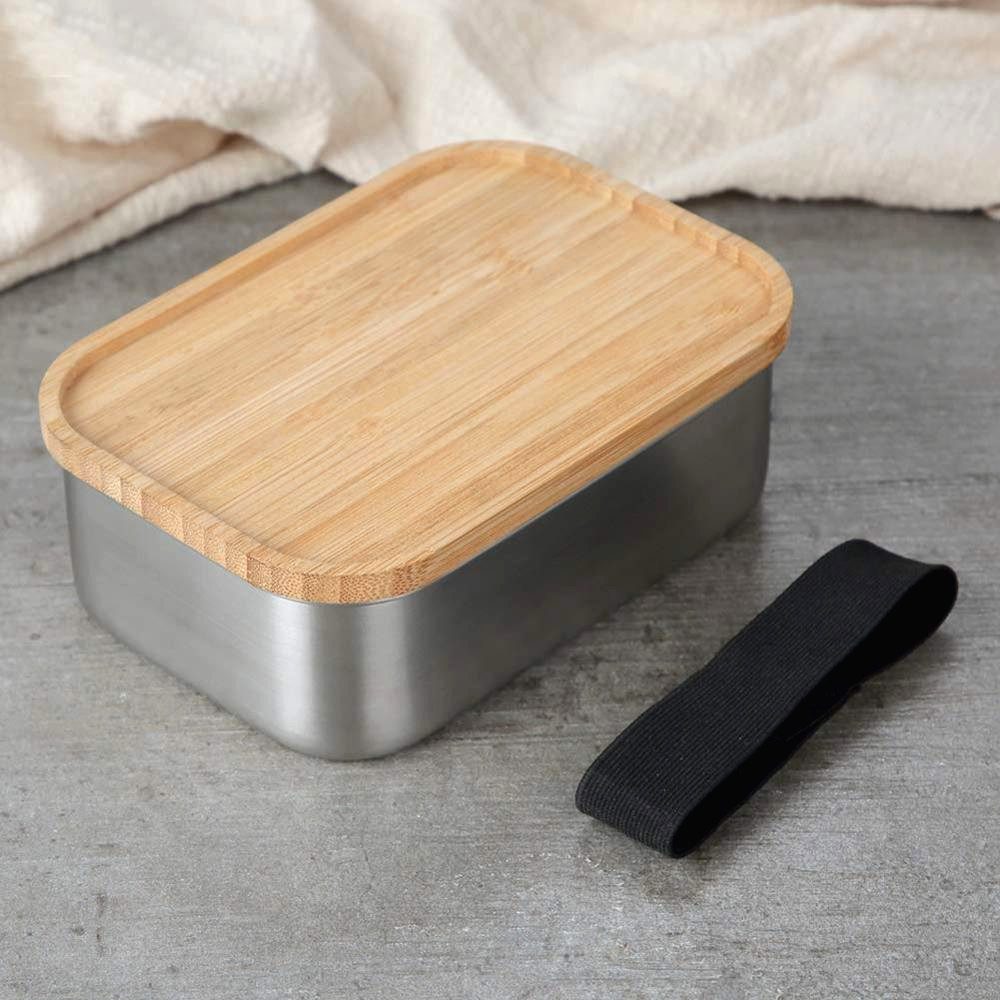 Bento en acier inoxydable avec couvercle en bambou et sangle noire posée à côté