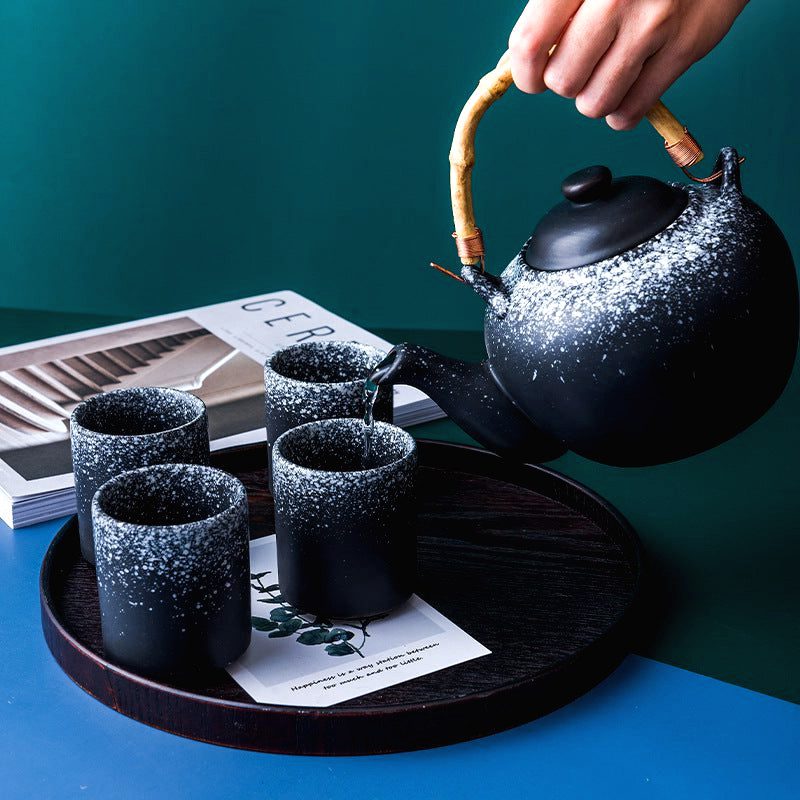 Théière japonaise Tamashiro tenue au-dessus de quatre tasses sur un plateau
