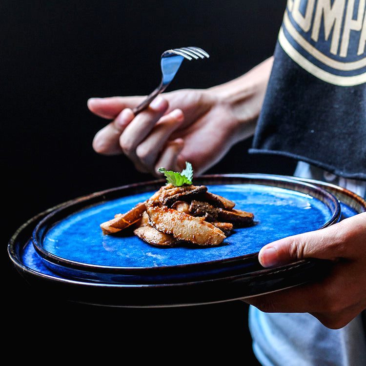 Assiette japonaise Aozora bleue garnie de viande, tenue en main avec une fourchette