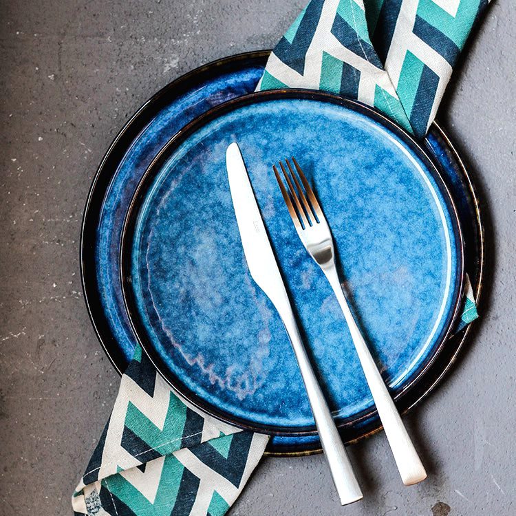 Assiettes japonaises Aozora bleues empilées sur une serviette à chevrons avec couverts