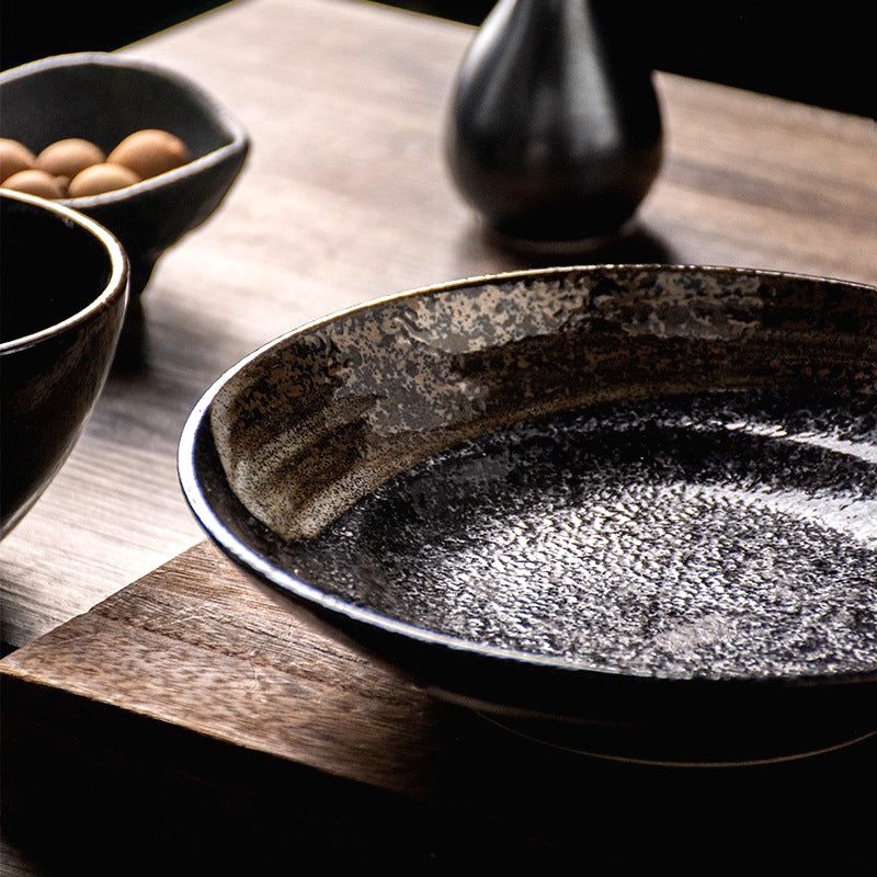 Assiette creuse Honmono noire mouchetée vue de près sur une table en bois sombre
