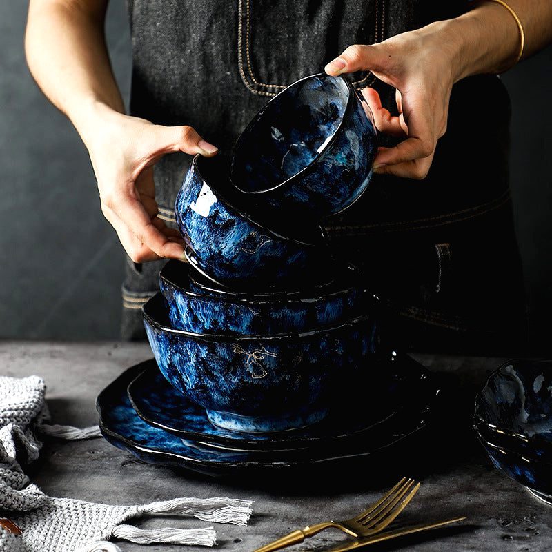 Bols Mahōtsukai bleus empilés sur des assiettes, tenus à deux mains