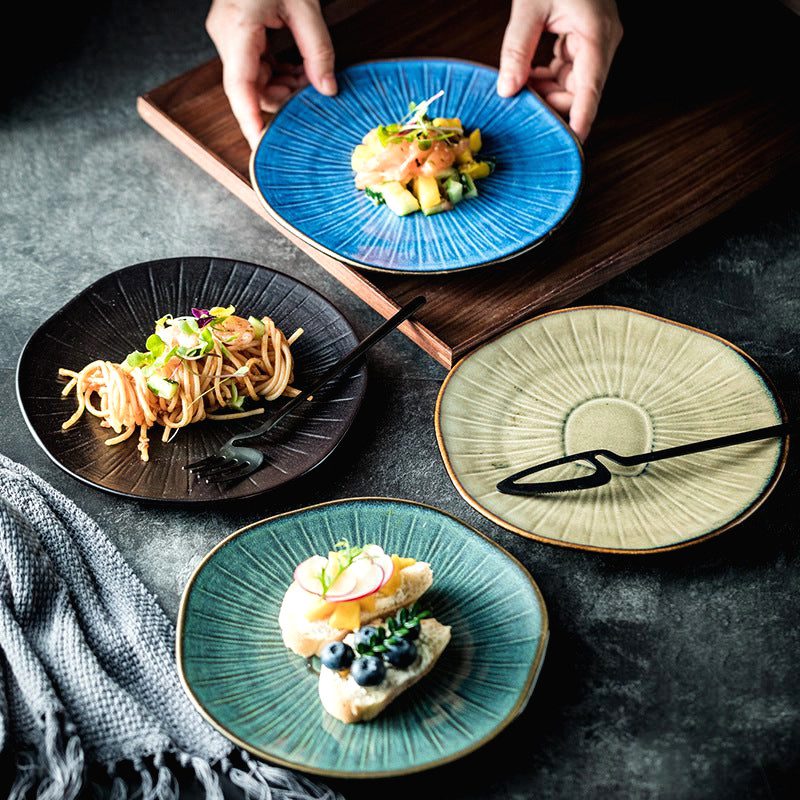 Assiette japonaise Nikkō bleue tenue à deux mains au-dessus de trois autres coloris garnis