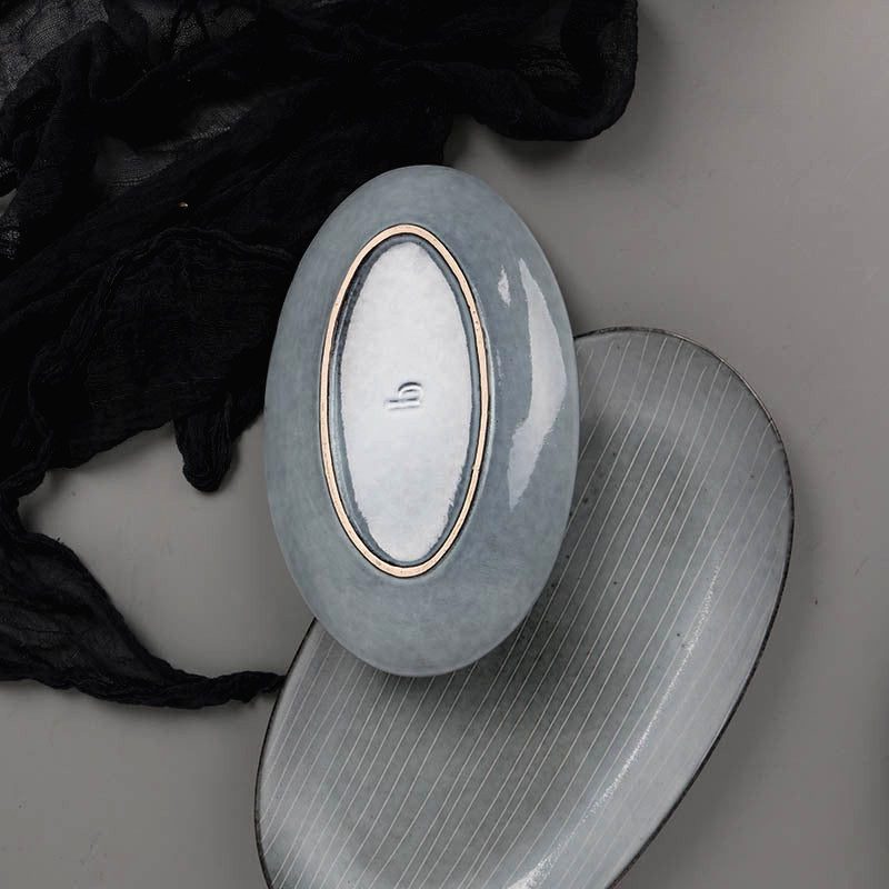 Plat ovale et assiette Sora posés sur un tissu noir