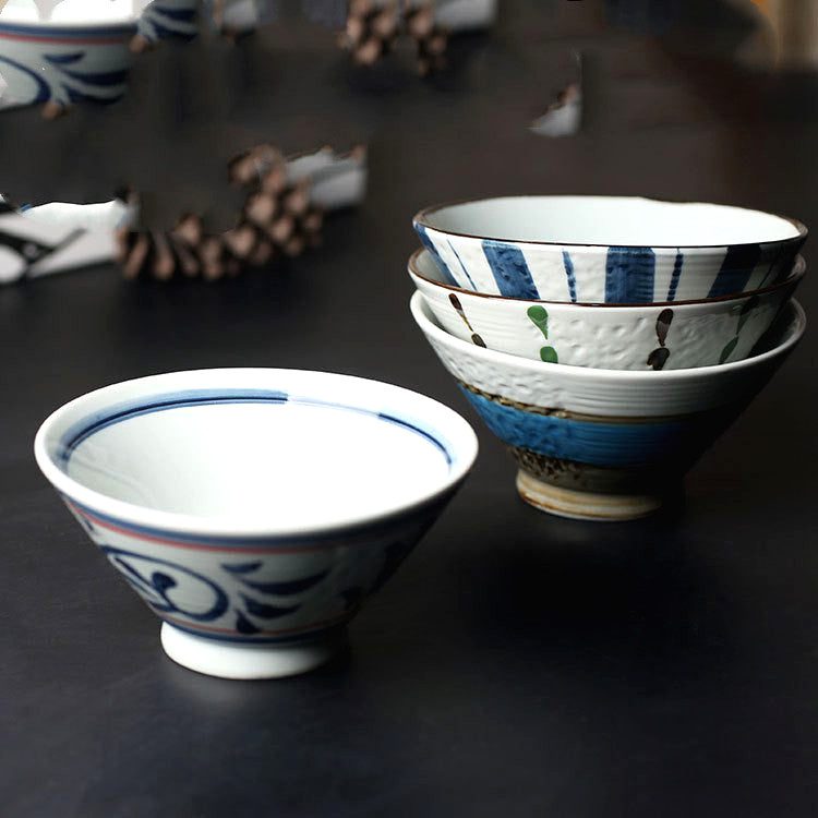 Bols à riz Nashio empilés et un bol à motif bleu au premier plan