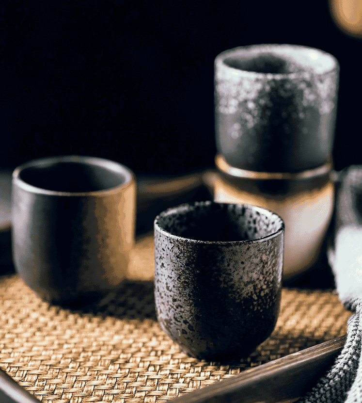 Trois tasses Ishikura sur une natte tressée, fond sombre
