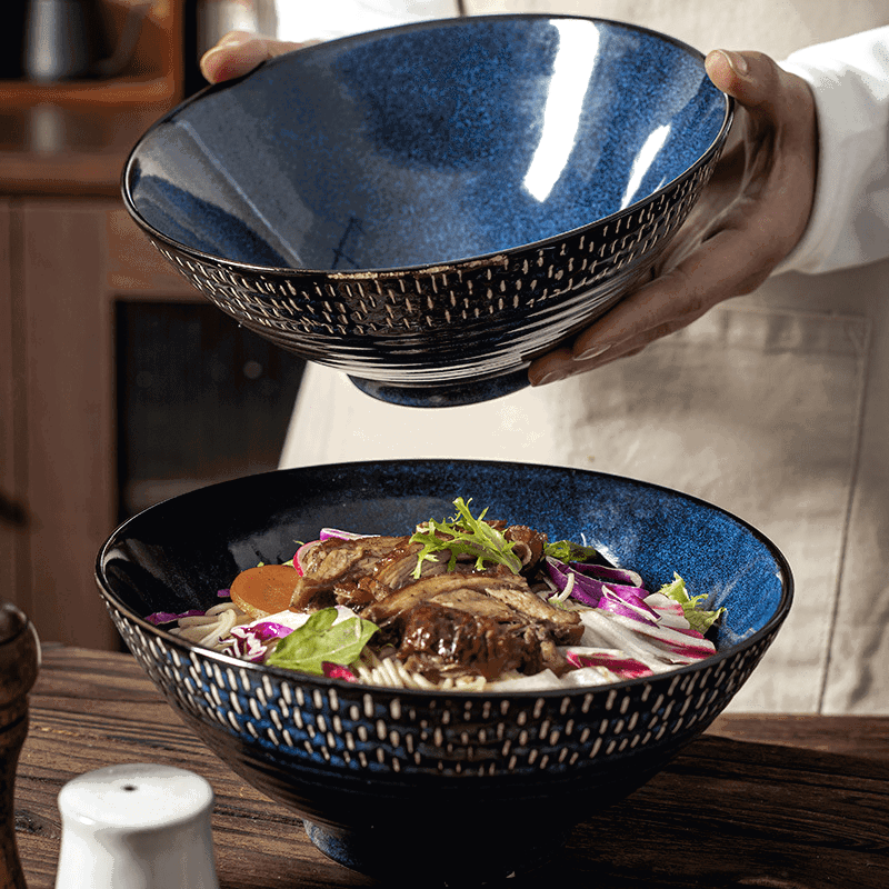 Deux bols à ramen Miyasato bleus, l'un garni de salade sur une table