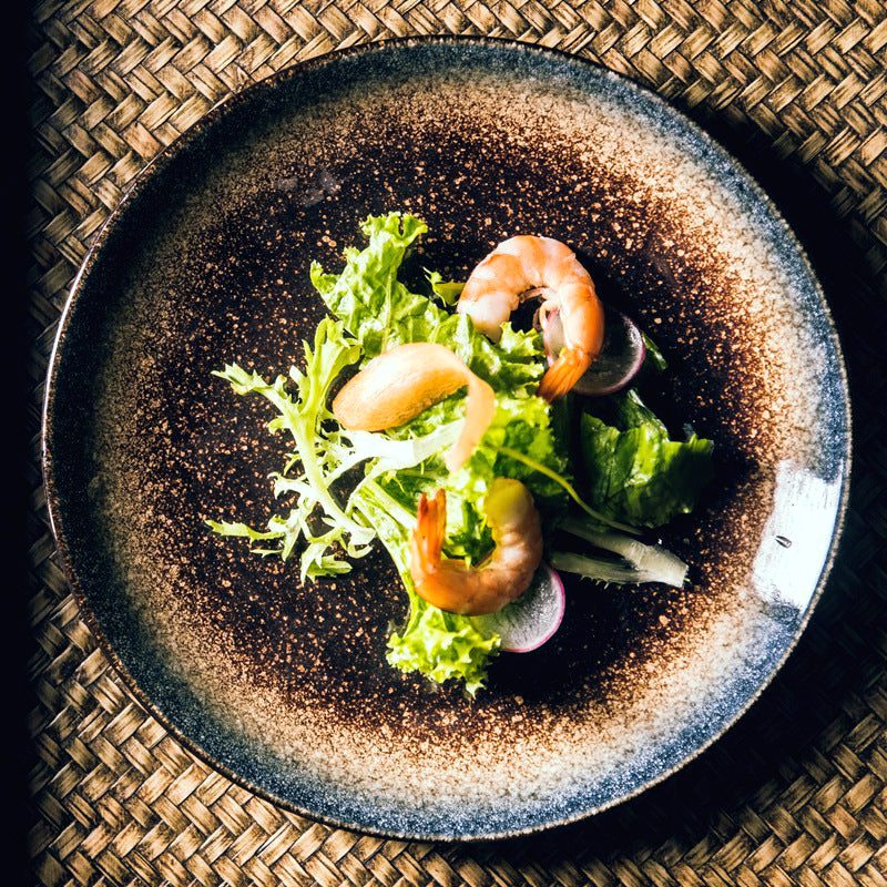 Assiette Nomi garnie de crevettes et de salade sur une natte tressée