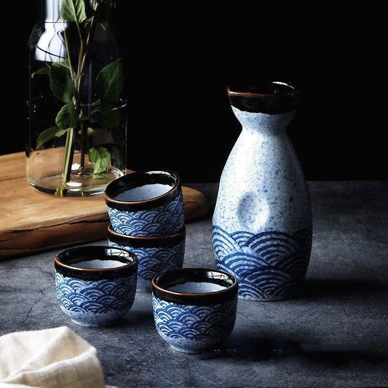 Service à saké Isa sur fond sombre près d'un vase de verdure