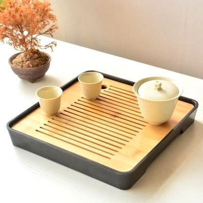 Plateau à thé en bambou avec tasses et bol couvert, bonsaï en arrière-plan