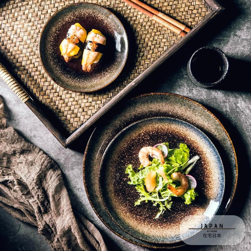 Deux assiettes Nomi garnies de salade et de sushis sur un plateau tressé