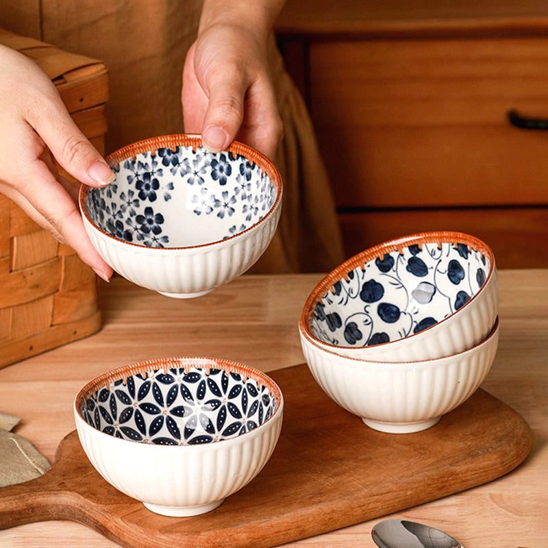 Bols Tama à motifs bleus empilés sur une planche, l'un tenu à deux mains