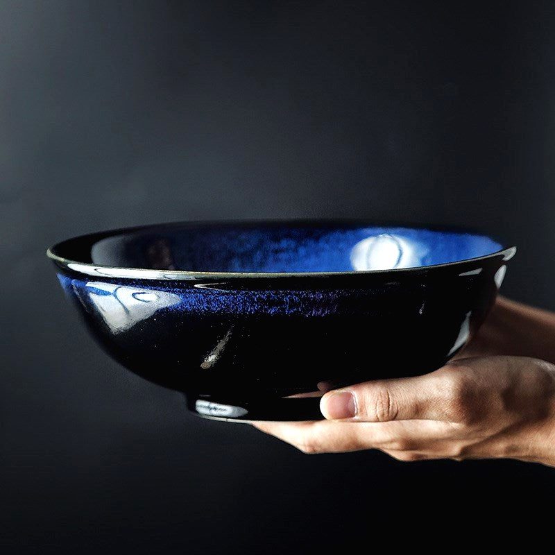 Bol à nouilles Mase bleu tenu à deux mains, vu de profil