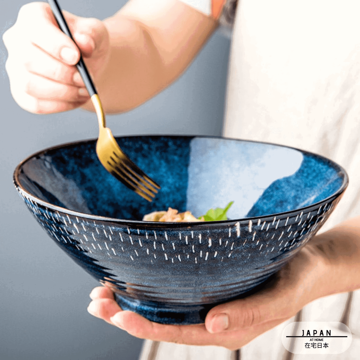 Bol à ramen Miyasato bleu tenu en main, fourchette et nouilles à l'intérieur