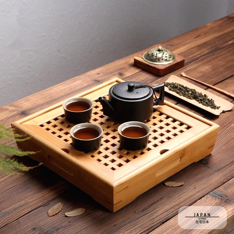 Plateau à thé en bambou avec théière noire et trois tasses de thé