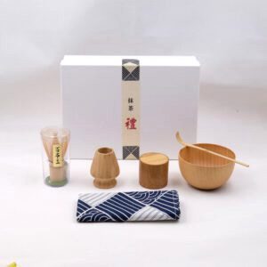 Kit matcha en bambou déballé devant son coffret blanc, tissu à vagues bleues