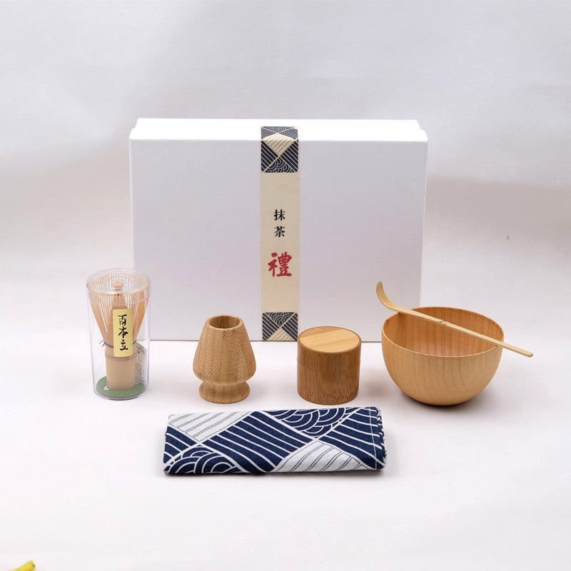 Kit matcha en bambou déballé devant son coffret blanc, tissu à vagues bleues