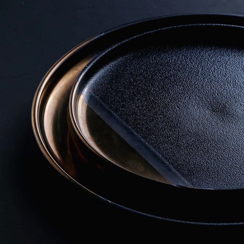 Détail de deux assiettes japonaises Yuna empilées, reflets noirs et dorés