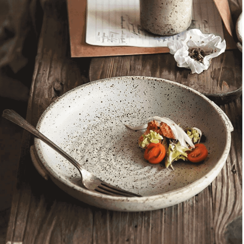 Assiette japonaise Watsuji blanc cassé garnie de tomates et salade sur une table en bois
