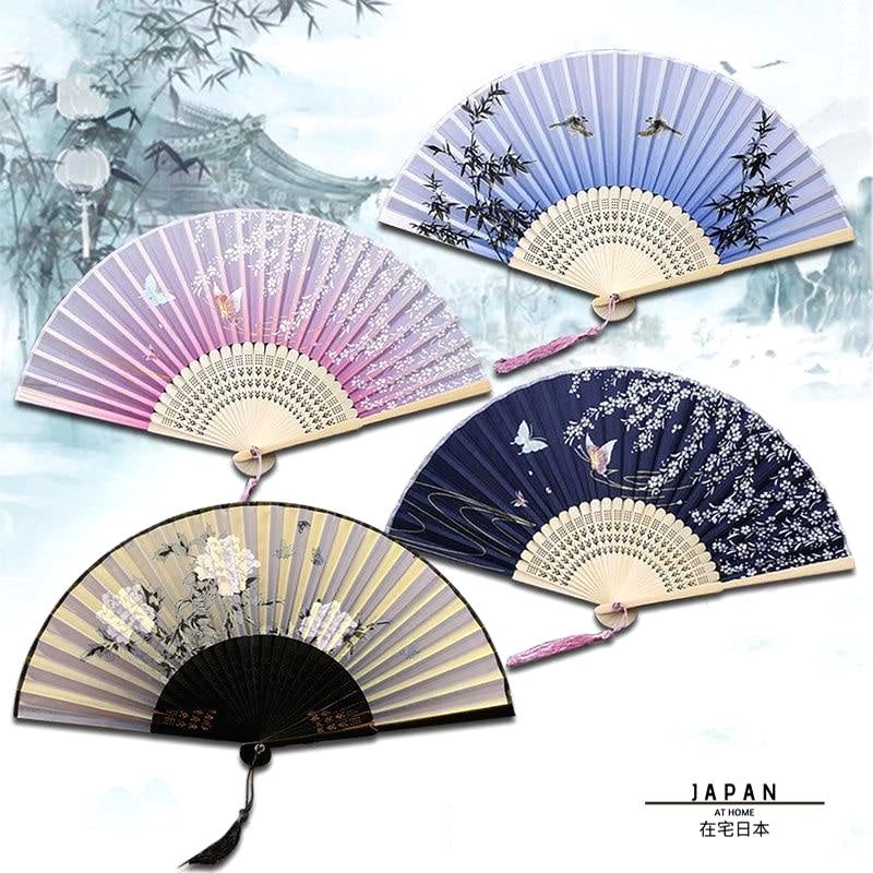 Quatre éventails japonais en bambou et satin ouverts sur fond de paysage