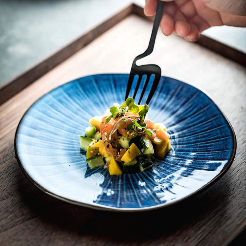 Assiette japonaise Nikkō bleue garnie d'une salade de légumes, fourchette noire en main