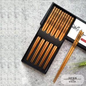 Coffret de baguettes japonaises gravées ouvert, une paire sortie de la boîte