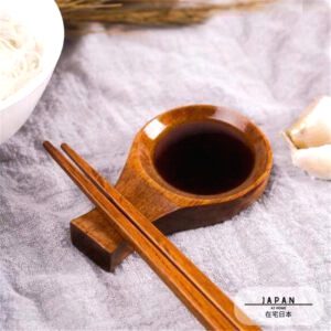Coupelle à sauce en bois remplie de sauce, baguettes posées sur le support