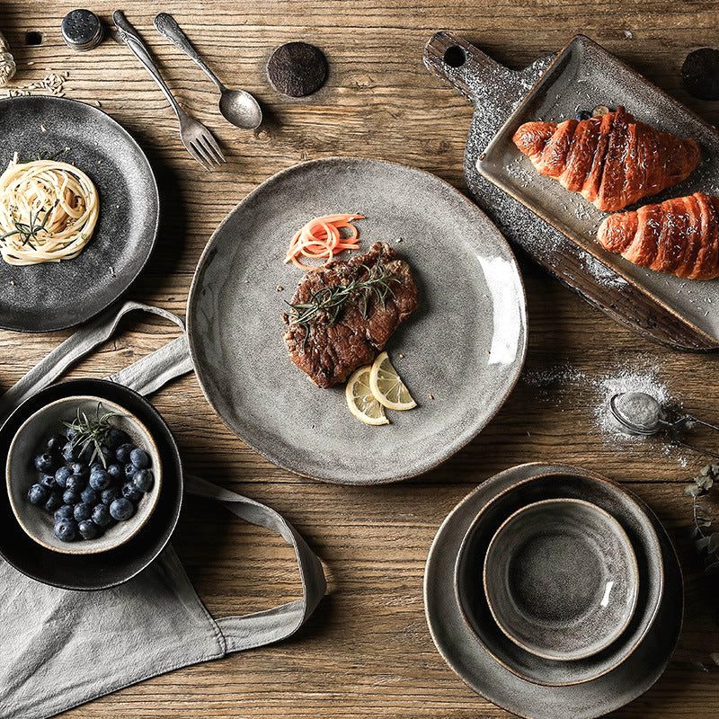 Assiettes japonaises Kobo grises et noires vues de dessus sur une table en bois avec croissants