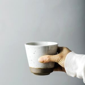Tasse japonaise Taira blanche mouchetée tenue dans une main