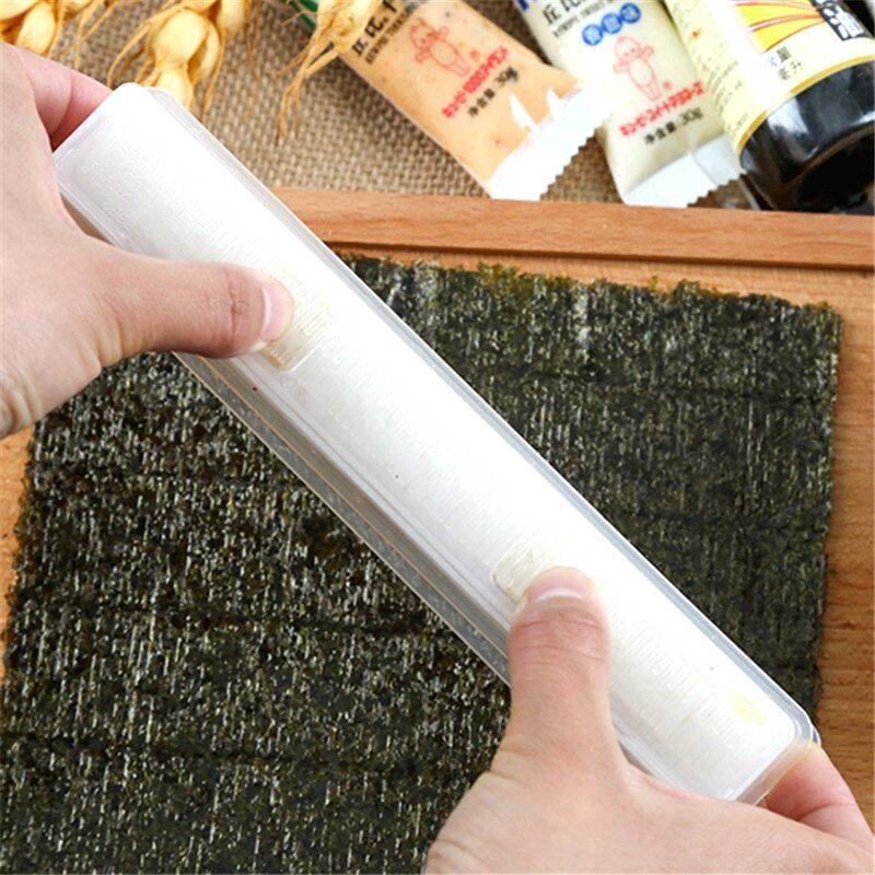 Moule à maki transparent tenu à deux mains sur une feuille d'algue