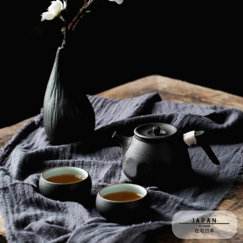 Service à thé Fukui noir posé sur un linge gris près d'un vase