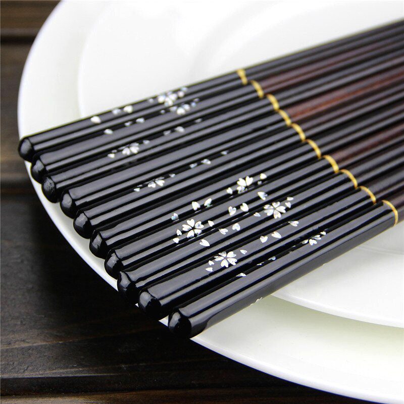 Baguettes en bois laqué noir à fleurs blanches posées sur une assiette