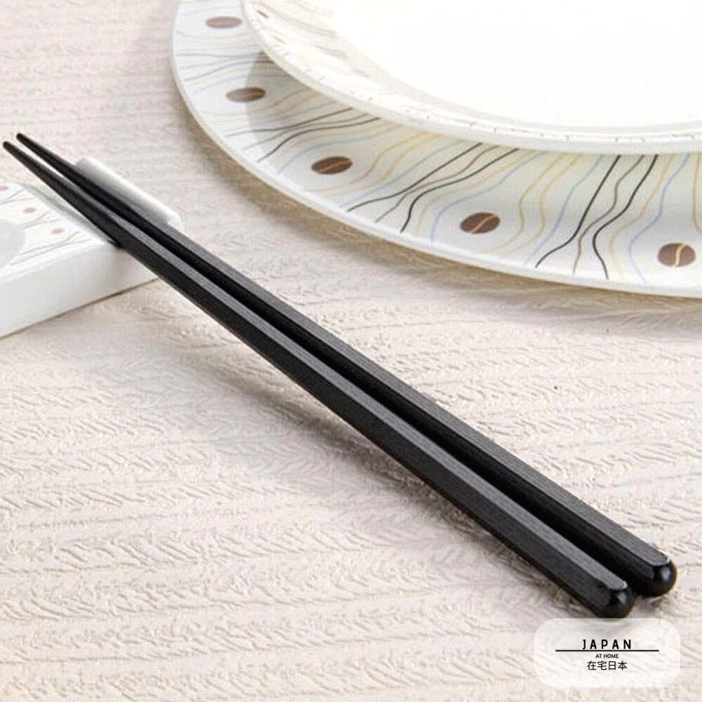 Baguettes japonaises Meiji noires posées près d'une assiette décorée