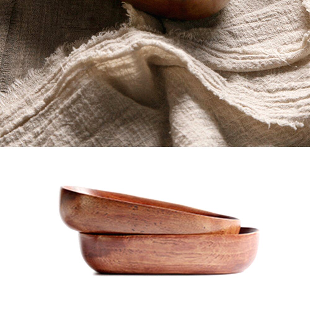 Deux bols canoë en bois d'acacia empilés sous un tissu beige