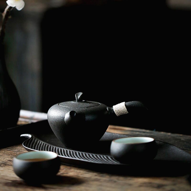 Plateau feuille avec théière noire et tasses, vue rapprochée