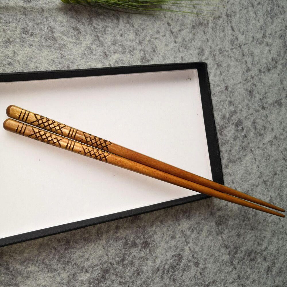Paire de baguettes japonaises à motif gravé posée sur la boîte ouverte