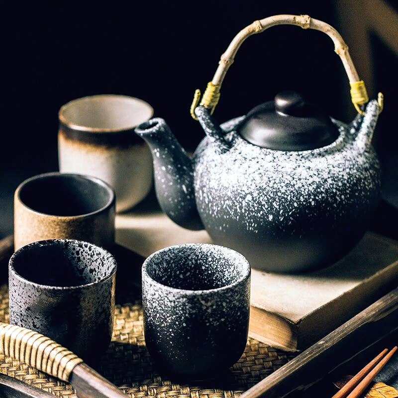 Tasses Ishikura autour d'une théière à anse sur fond sombre