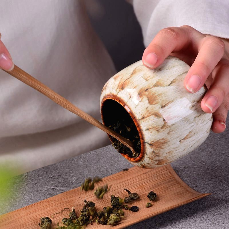 Boîte à thé Hattori versant des feuilles de thé sur une pelle en bambou